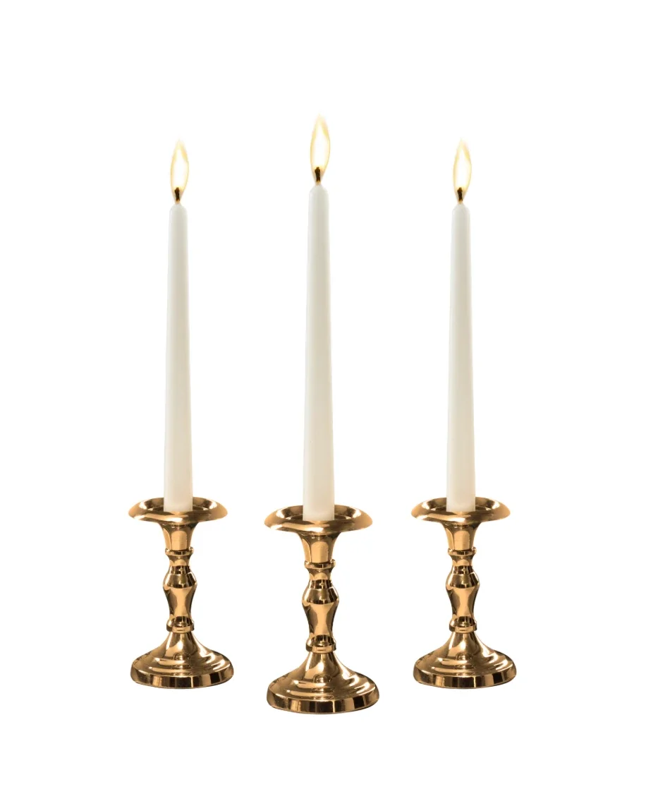 Three lit white candles in gold candle holders against a white background.