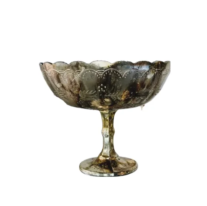 A vintage glass bowl with a scalloped edge and decorative patterns, mounted on a short stem and round base.