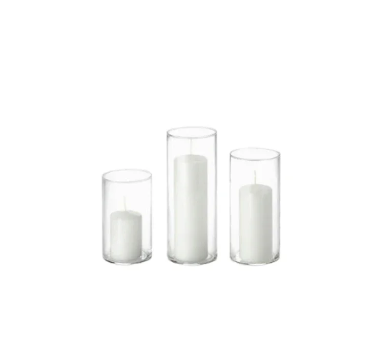 Three glass candleholders of varying heights with white candles inside