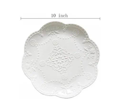 White decorative plate with intricate embossed floral and scroll patterns, approximately 10 inches in diameter.