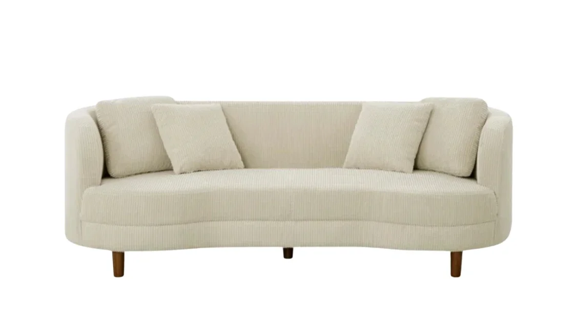 Cream-colored sofa with four cushions against a white background.