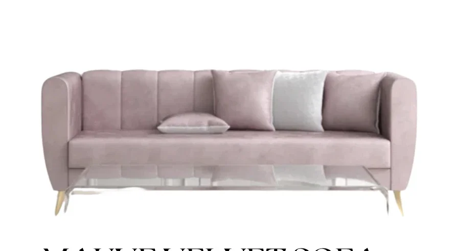 A light pink velvet sofa with wooden legs, accompanied by three pillows in matching and contrasting colors.