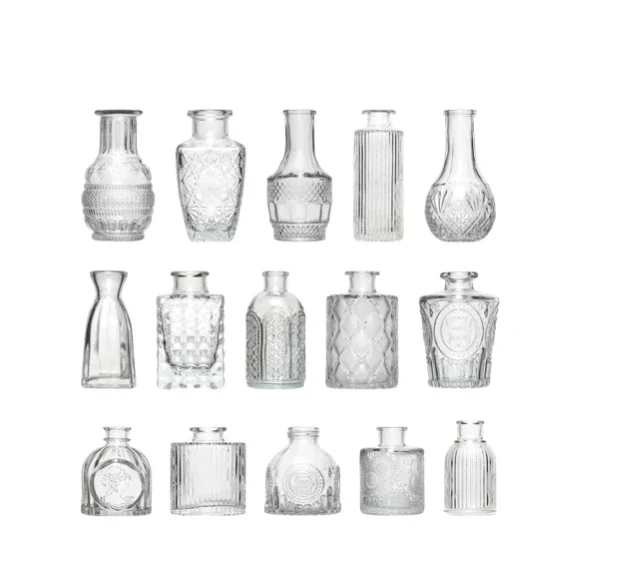 Collection of 14 clear glass bottles with various patterns and shapes against a white background.