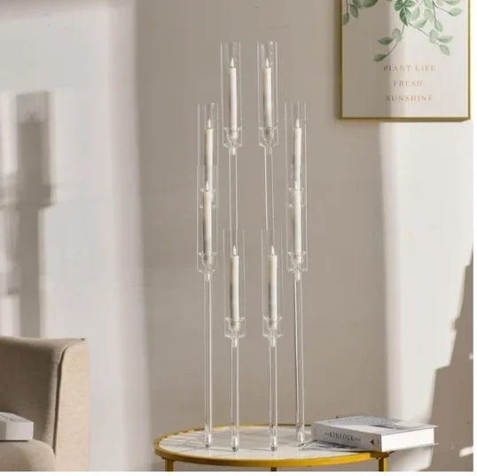 Set of tall, clear glass candlesticks with white candles, placed on a round side table in a living room.