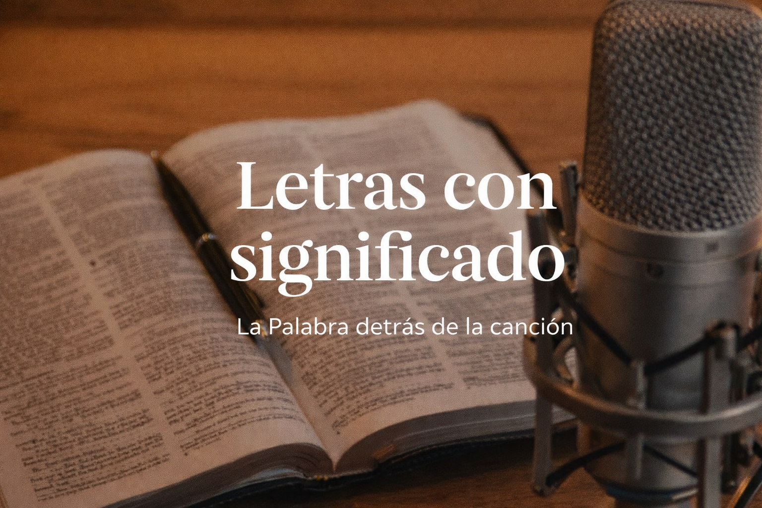 Open book, pen, studio microphone on a wooden background, and text in Spanish that reads 'Lyrics with meaning, The words behind the song'.