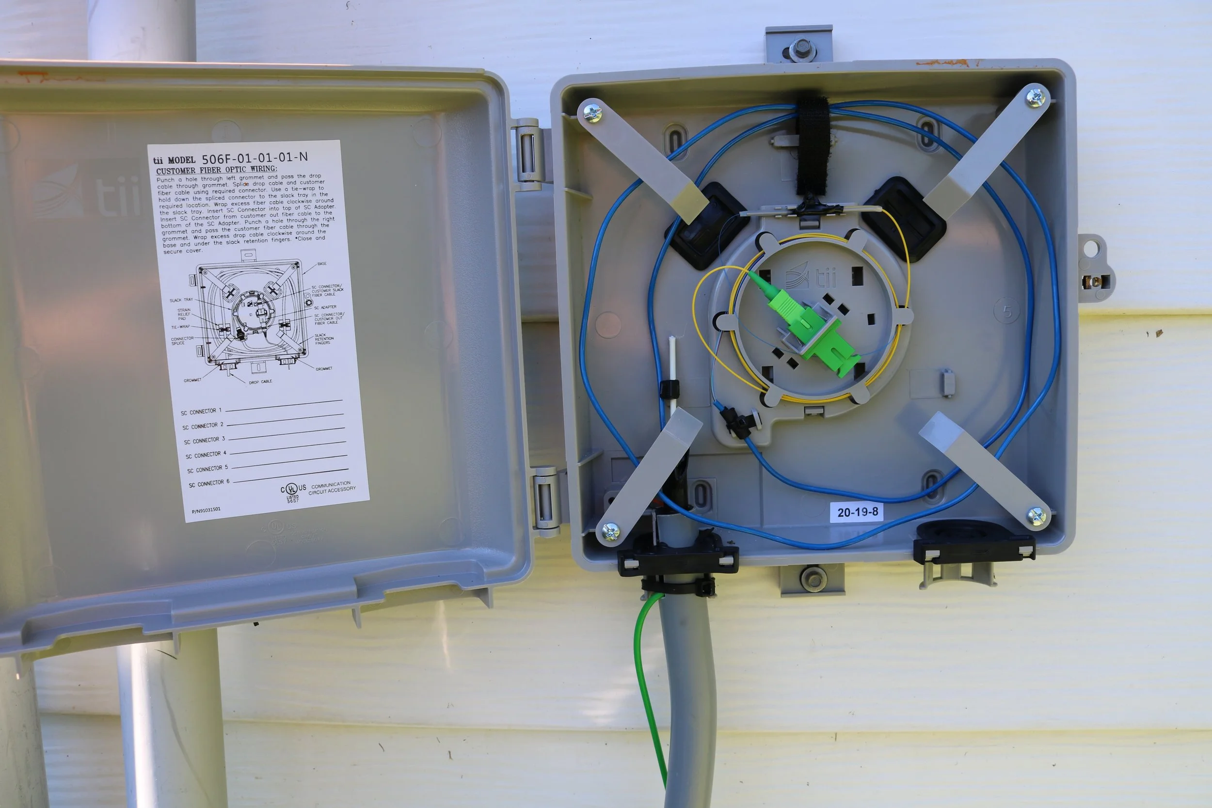 Open fiber optic distribution box showing cable connections and splicing tray