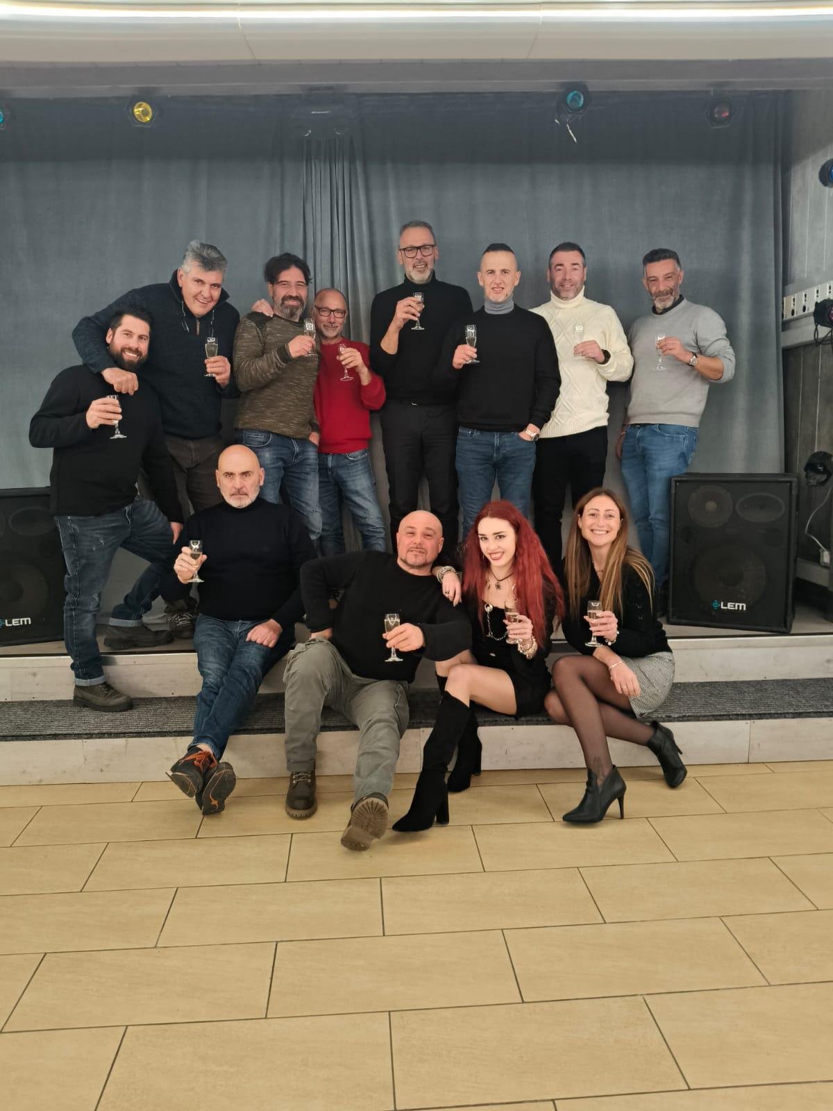 Gruppo di persone sorridenti che brindano con bicchieri di champagne durante una festa o evento in un ambiente interno.