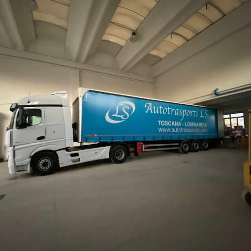 Un camion in un capannone con un logo e testo che indicano Autotrasporti LS di Toscana-Lombardia.