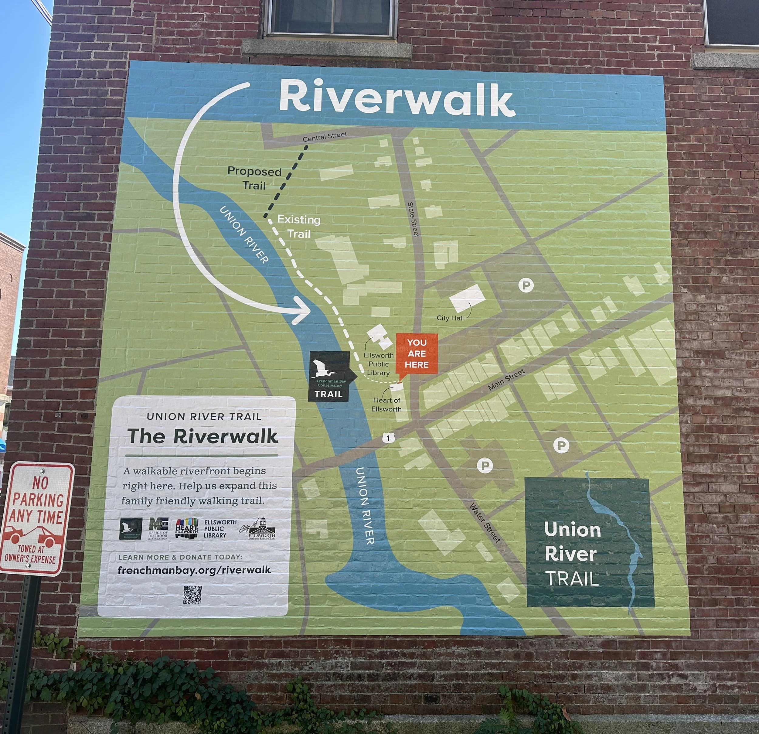 Map of the Riverwalk, showing the Union River along with existing and proposed trails, City Hall, Ellsworth Public Library, and parking areas; a red marker indicates the viewer's location with the label 'You Are Here'.
