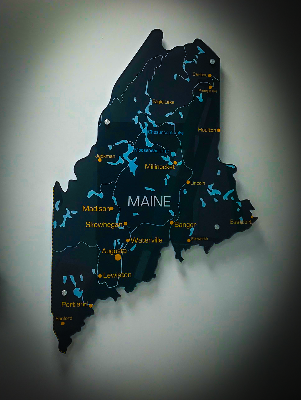 Map of Maine with lakes and cities labeled in yellow and blue, mounted on a wall.