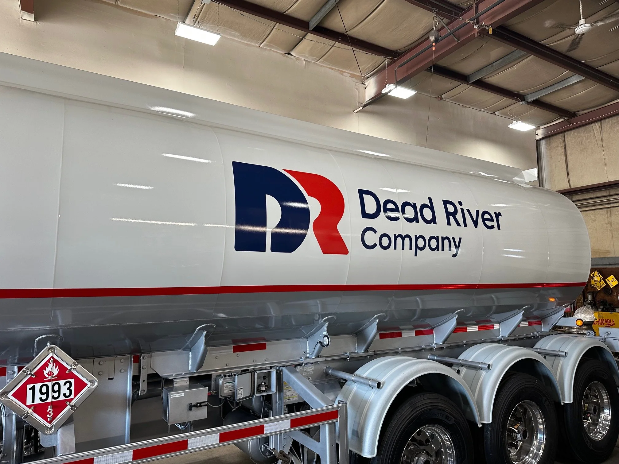 A large white fuel tanker truck with the logo and name 'Dead River Company' painted on the side, parked inside a warehouse or garage.