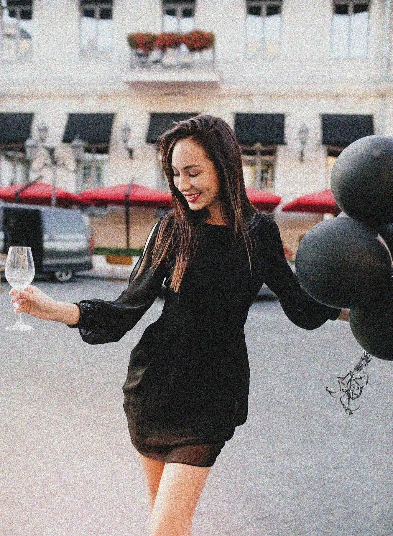 shapely-woman-fashionable-black-dress-dancing-city-square-waving-balloons.jpg