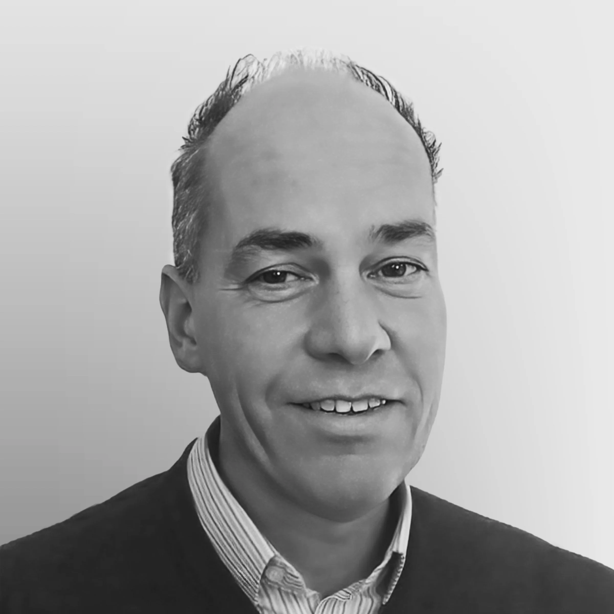 Black and white portrait of a smiling man in a collared shirt.