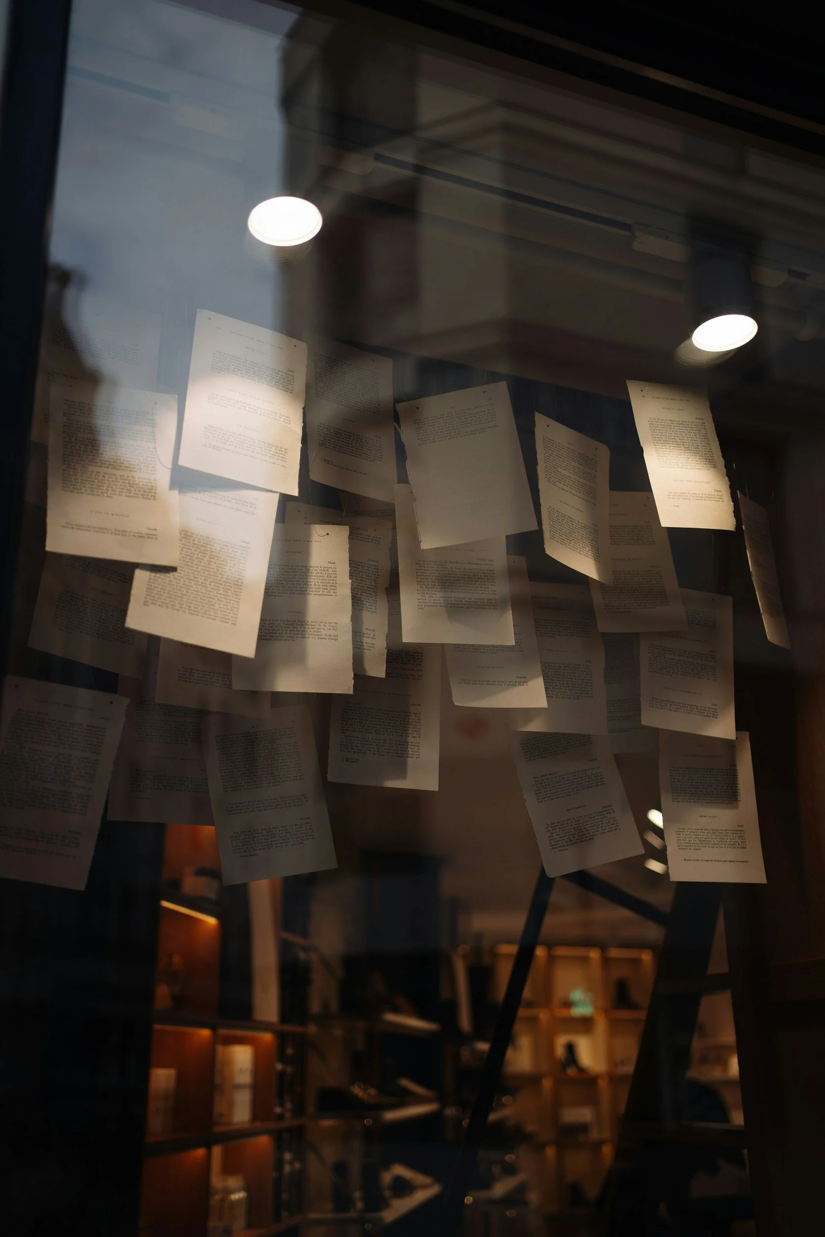 A dark room with pages of text suspended from the ceiling