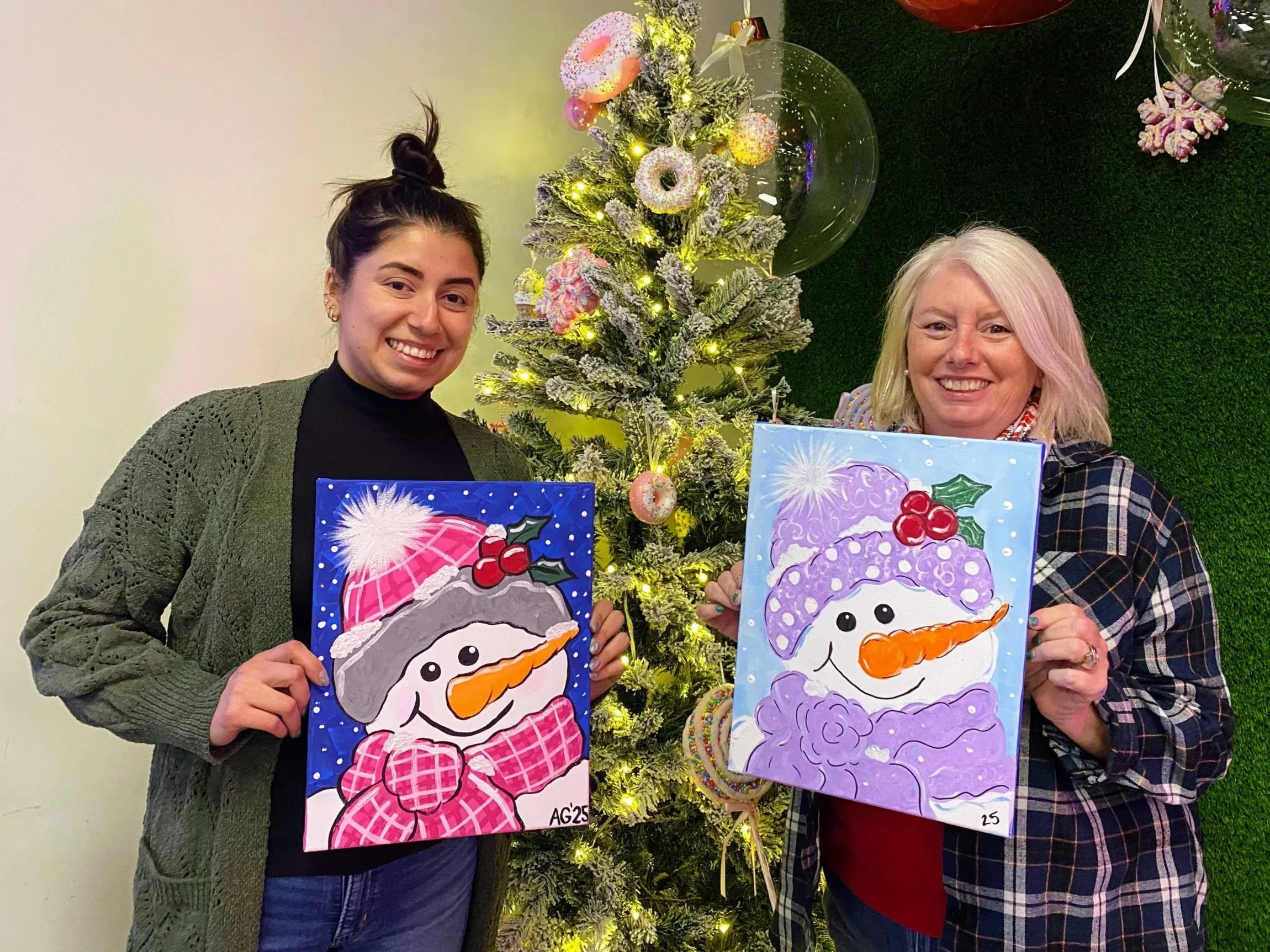 2 ladies holding snowmen paintings