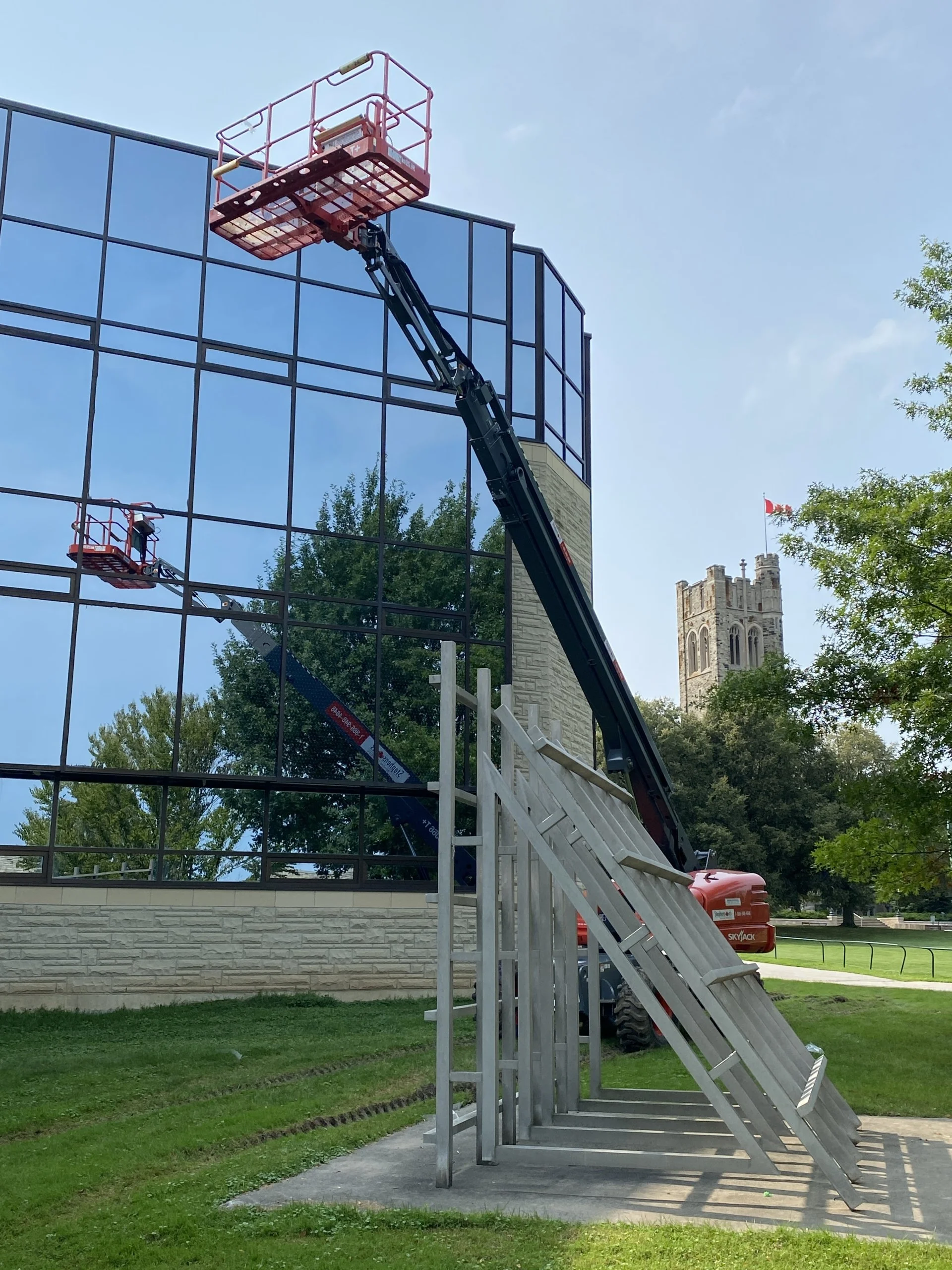Ladder construction equipment next to highly reflective windows on institutional building