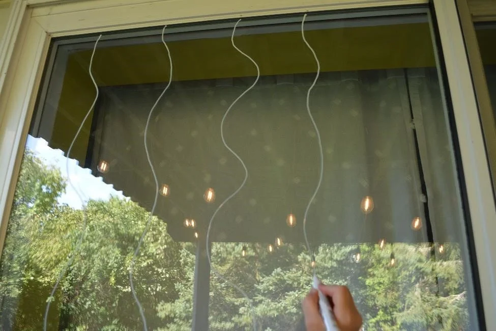Close up image of person drawing wavy lines with an oil based marker onto exterior windows of a home for bird-safe window treatment