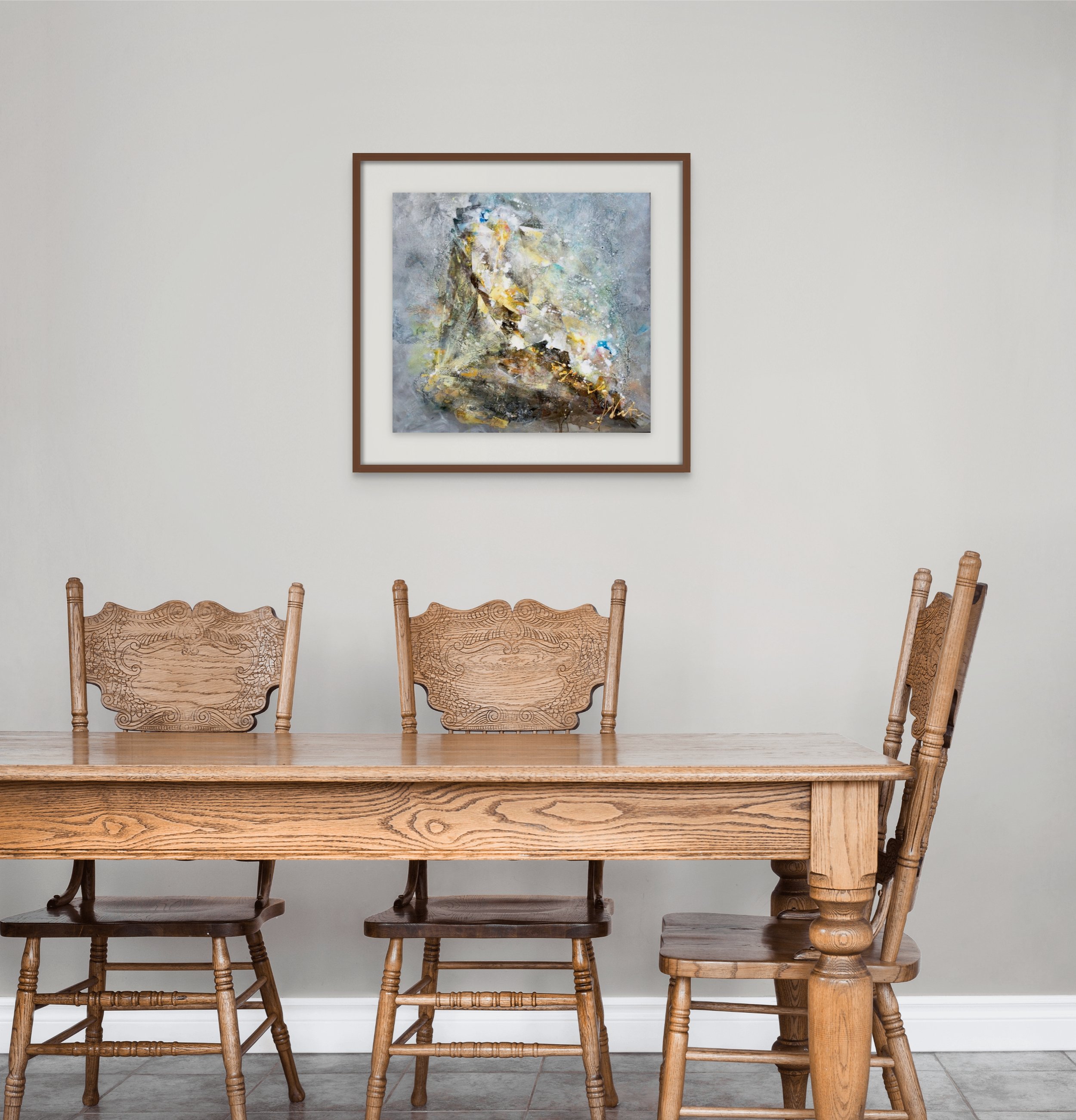 A wooden dining table with four matching chairs in front of a white wall. A colorful abstract painting hangs on the wall above the table.