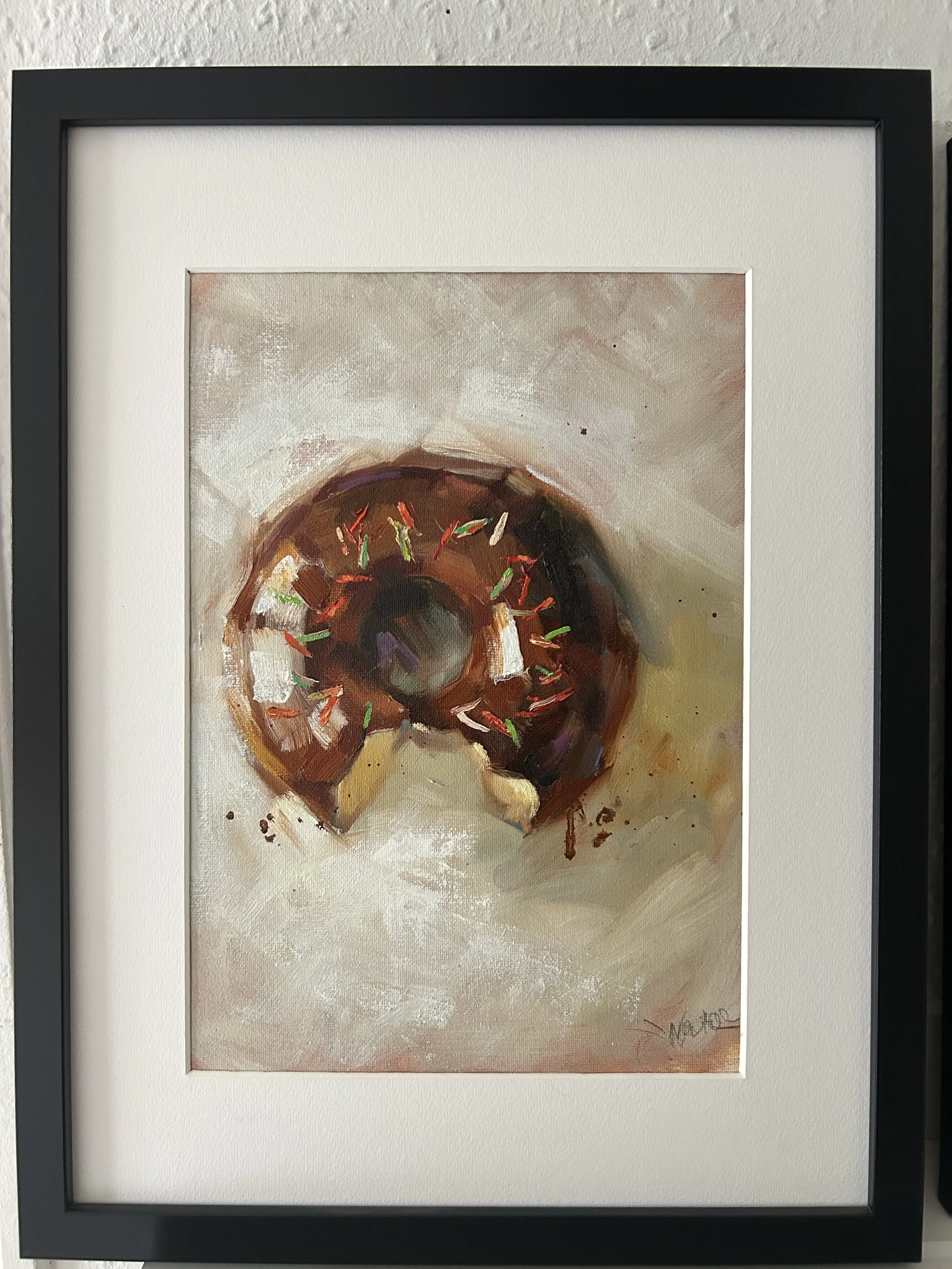 Akvarelmaleri af en chokoladekringle pyntet med farvede sukkerstriber, på en lys baggrund.