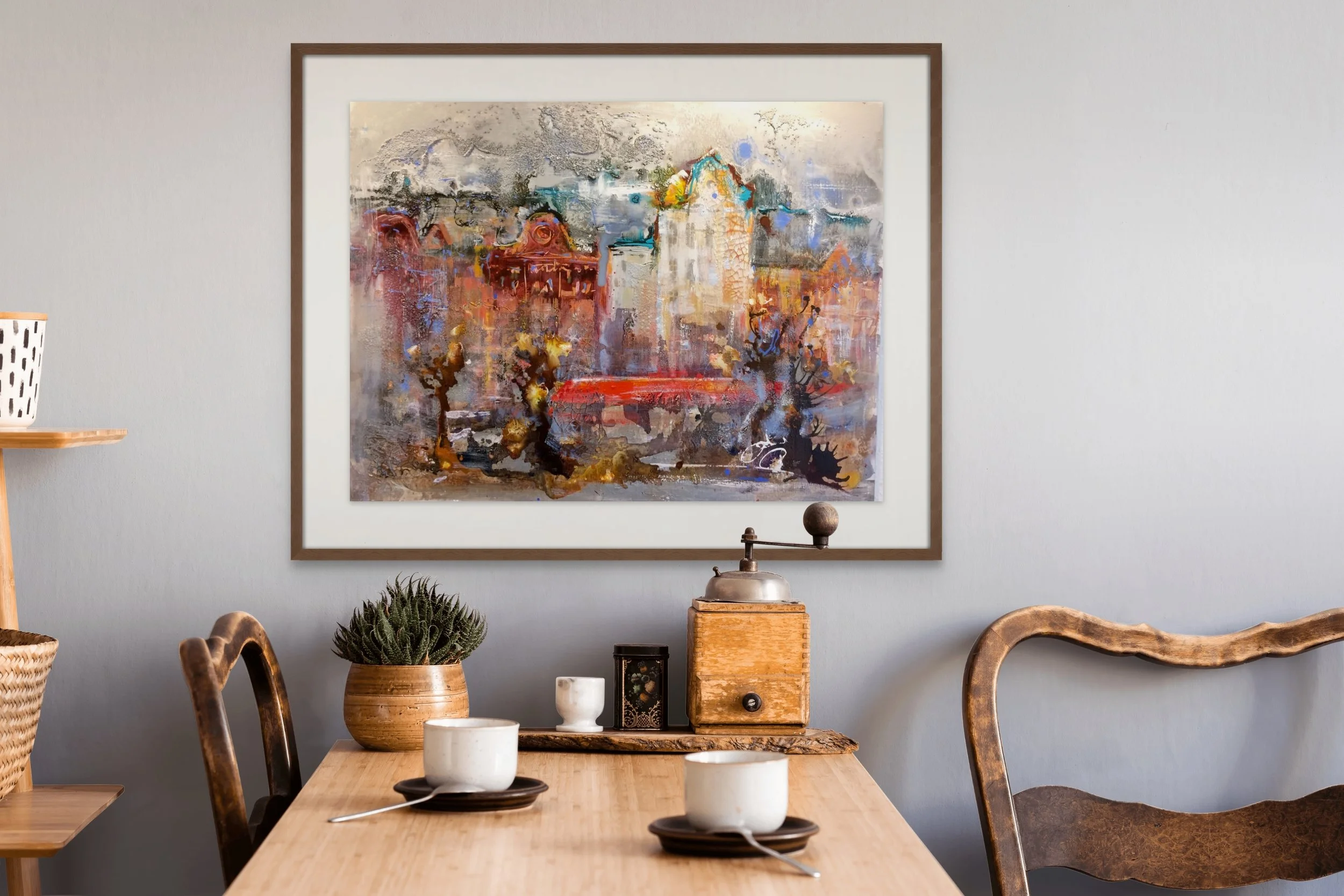 Interior dining room with wooden table, chairs, and decorative items. A framed abstract painting hangs on a light gray wall.