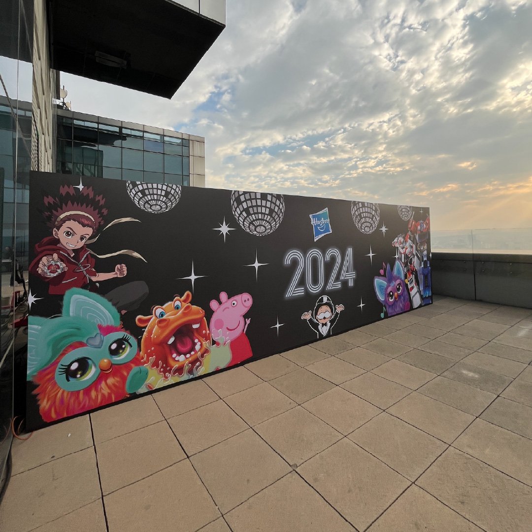 Muro decorativo con personajes de dibujos animados, el año 2024, y decoraciones como bolas de discoteca y estrellas.