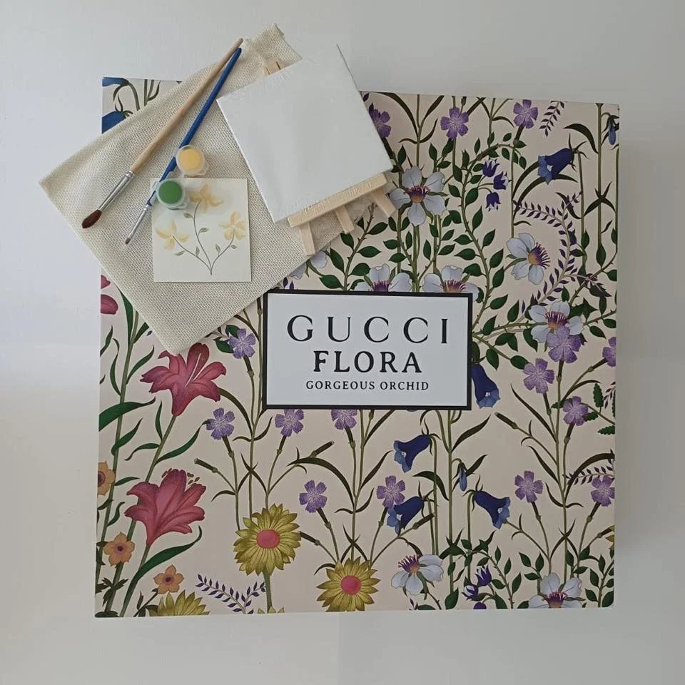 Caja de Gucci Flora con diseño de flores y letras en el centro que dice 'Giorgio Flora Gorgeous Orchid'.