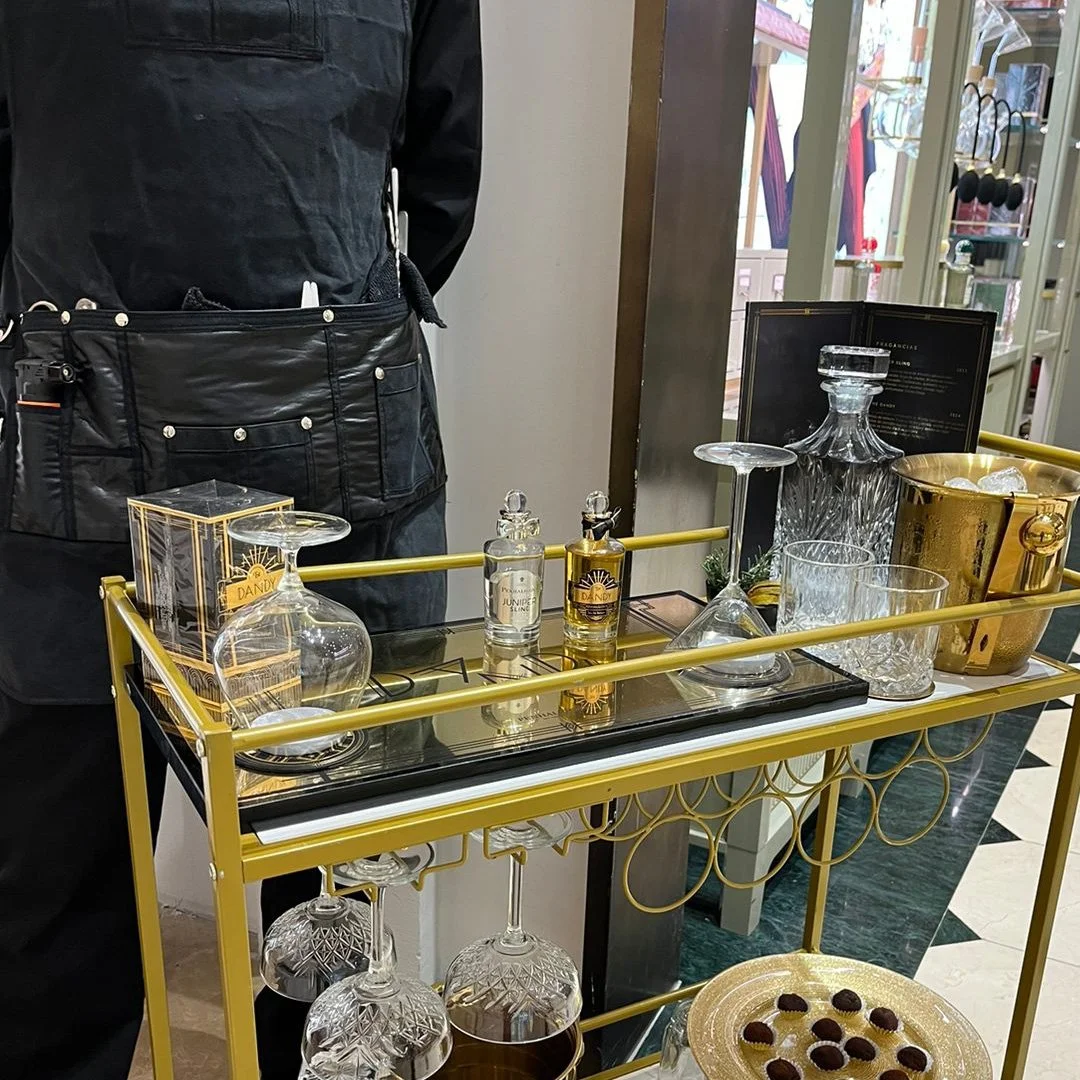 Carrito de bar con copas, botellas y chocolates en un establecimiento