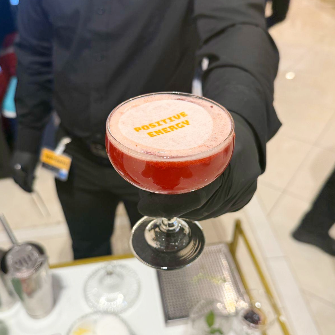 Una copa de cóctel rojo con la frase 'POSITIVE ENERGY' en la parte superior.