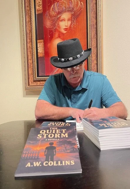 Author A.W. Collins, wearing a cowboy hat, signs copies of his award-winning book, "The Quiet Storm," at a table.