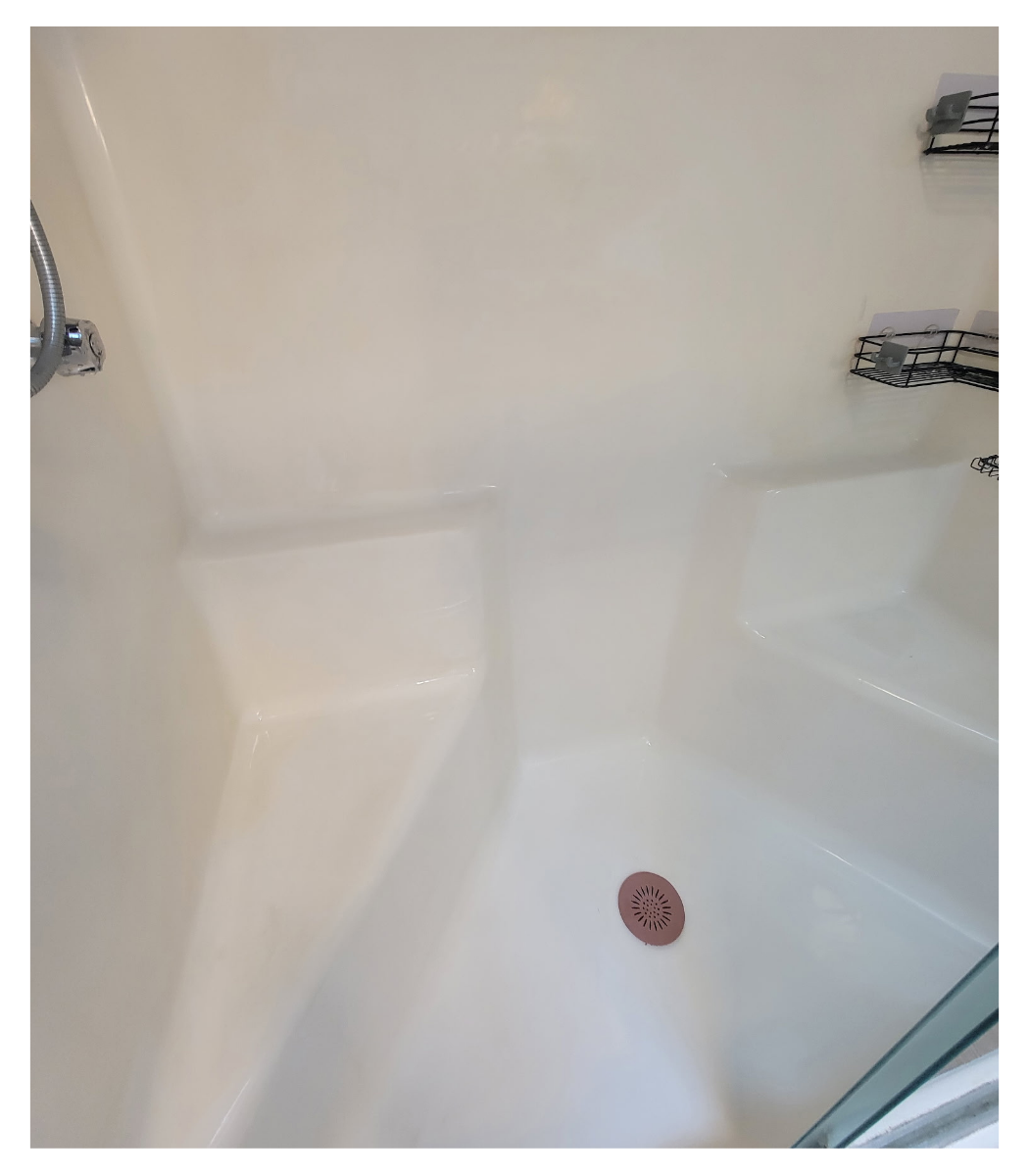 After picture of a very clean shower with a drain on the floor.