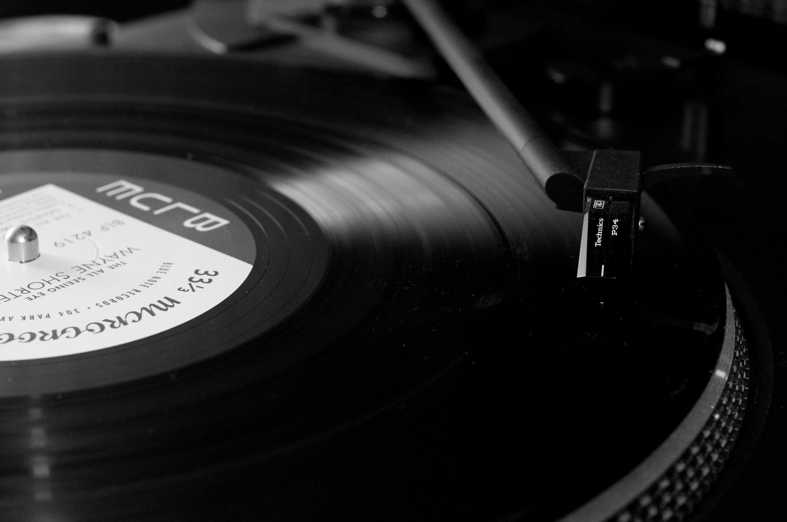 Close-up of a vinyl record playing on a turntable, with a tonearm and stylus in contact with the record surface.