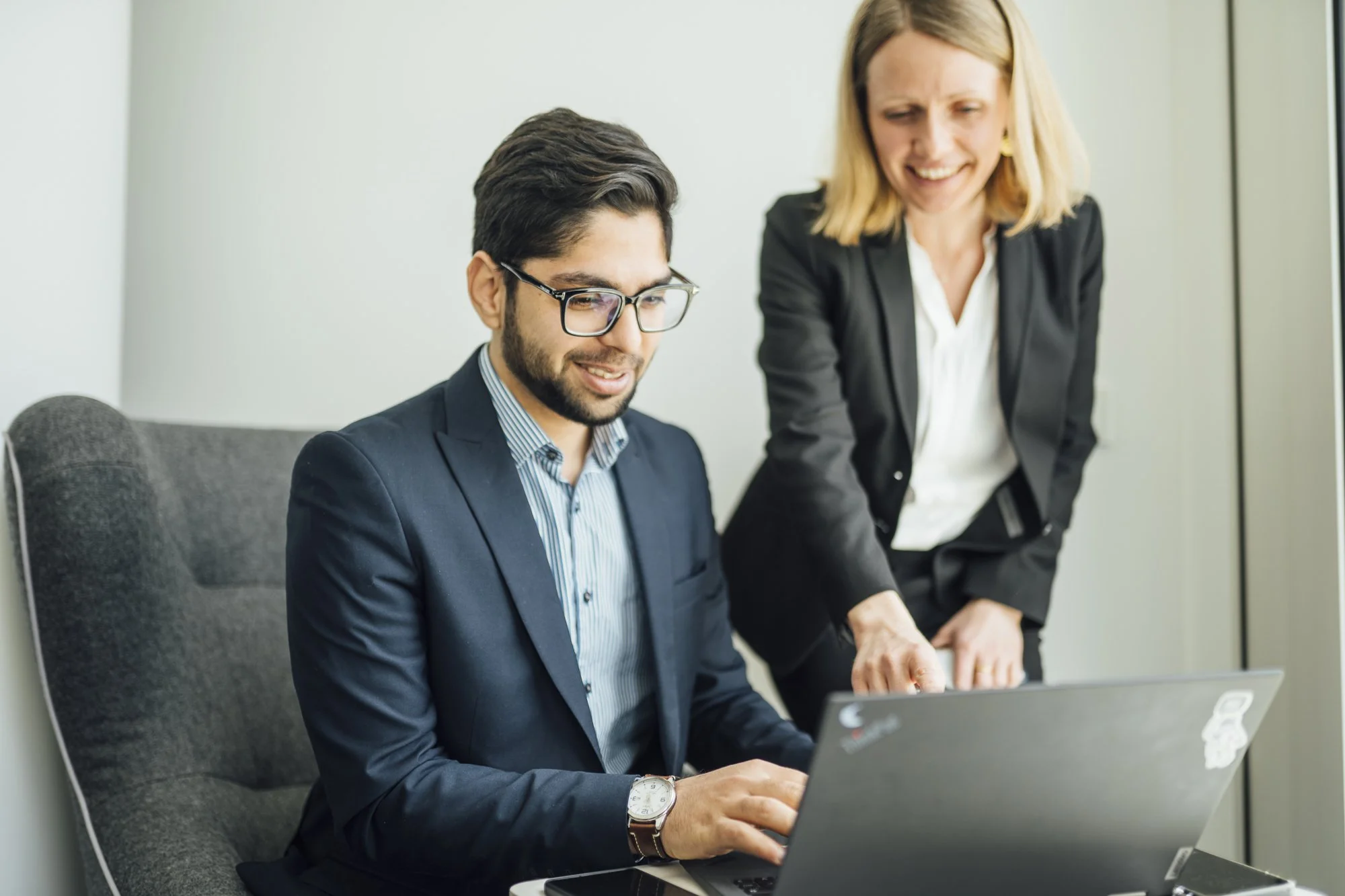 Zwei Geschäftsfrauen schauen gemeinsam auf einen Laptop in einem Büro.