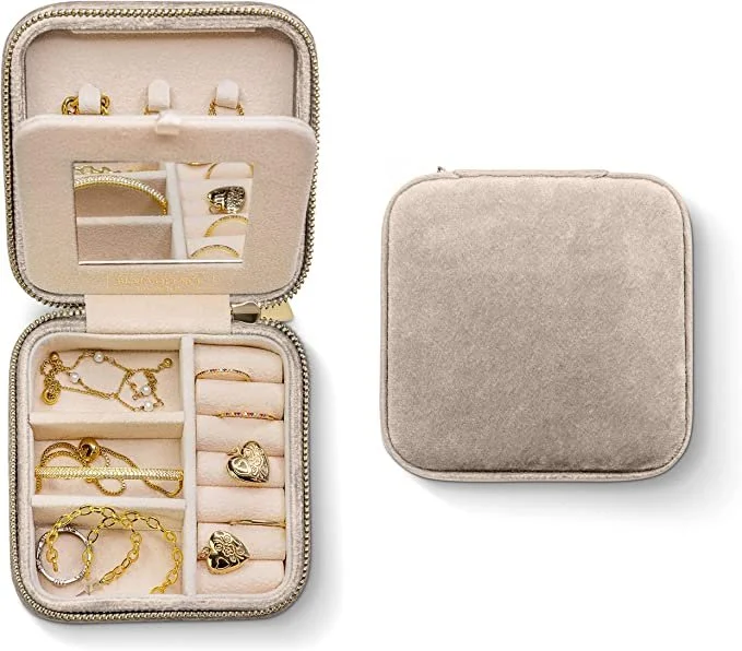Open jewelry box displaying various gold and silver necklaces, bracelets, rings, and earrings, with an empty gray jewelry case beside it.