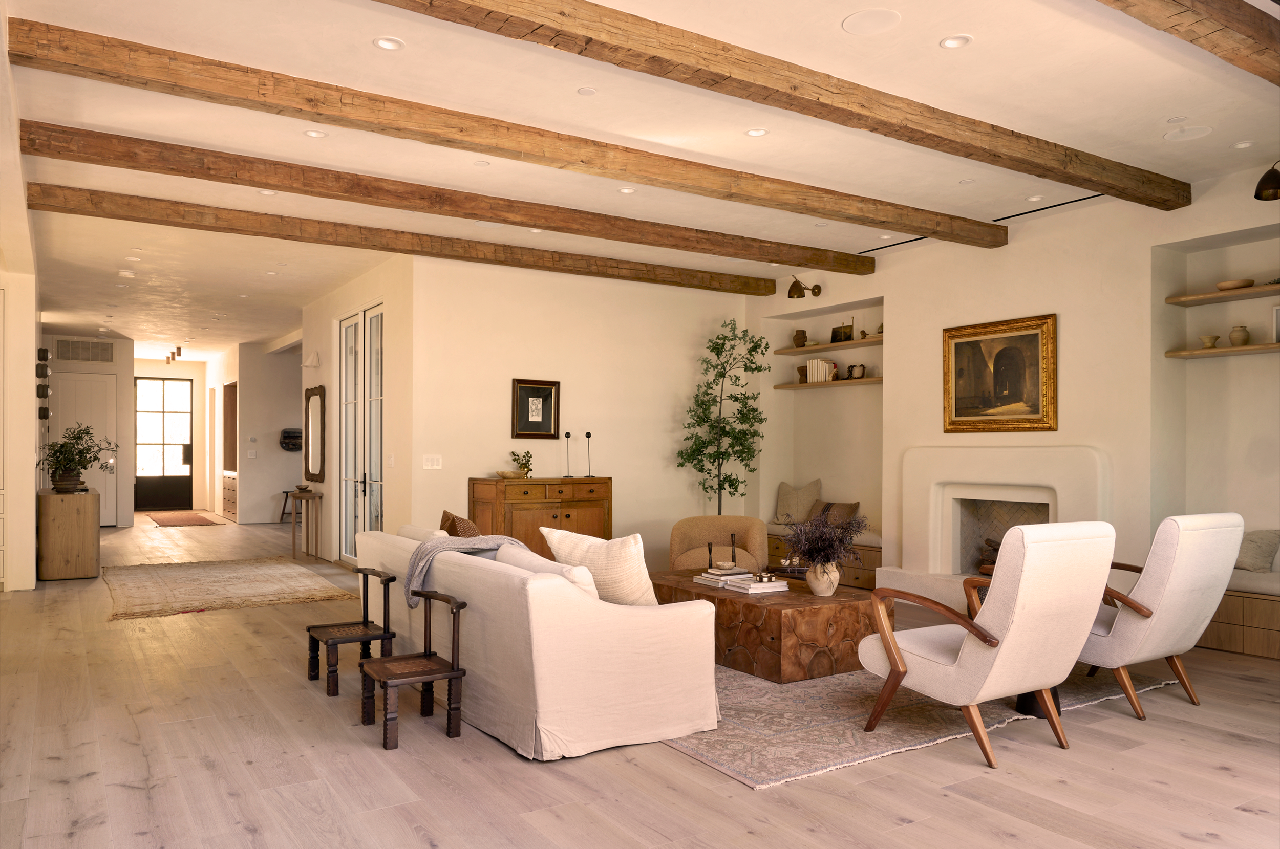 4338 Rhodes Ave, Studio City, a rustic wooden coffee table, and decorative wall shelves with pottery and books. There is a fireplace and framed artwork on the wall, with a doorway leading to the entryway.
