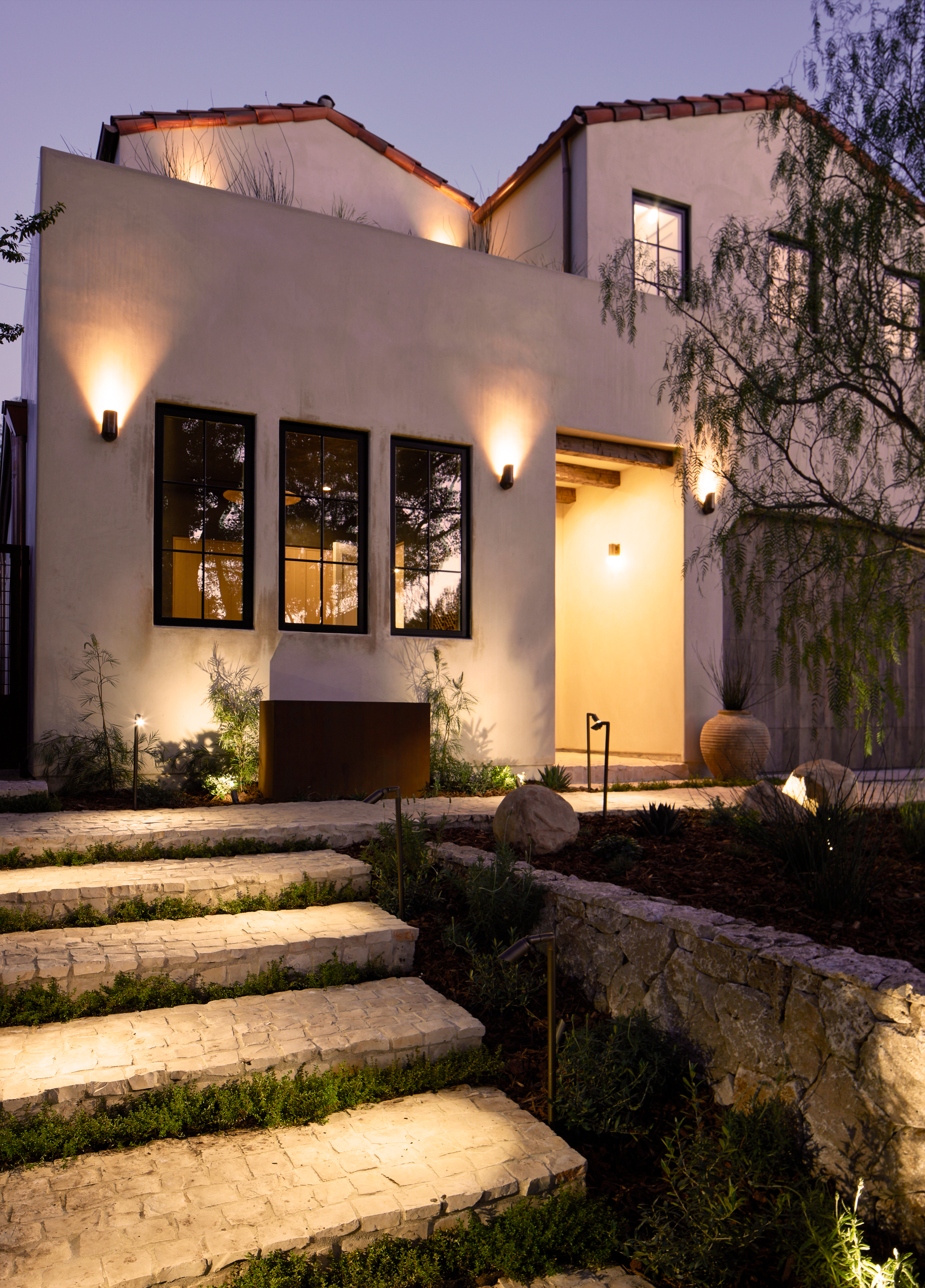 4338 Rhodes Ave, Studio City. Modern white house with large windows, pathway steps, outdoor lighting, and landscaped garden at dusk.