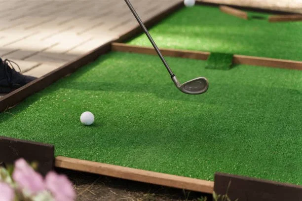 Miniature golf course with a golf ball and a putter.