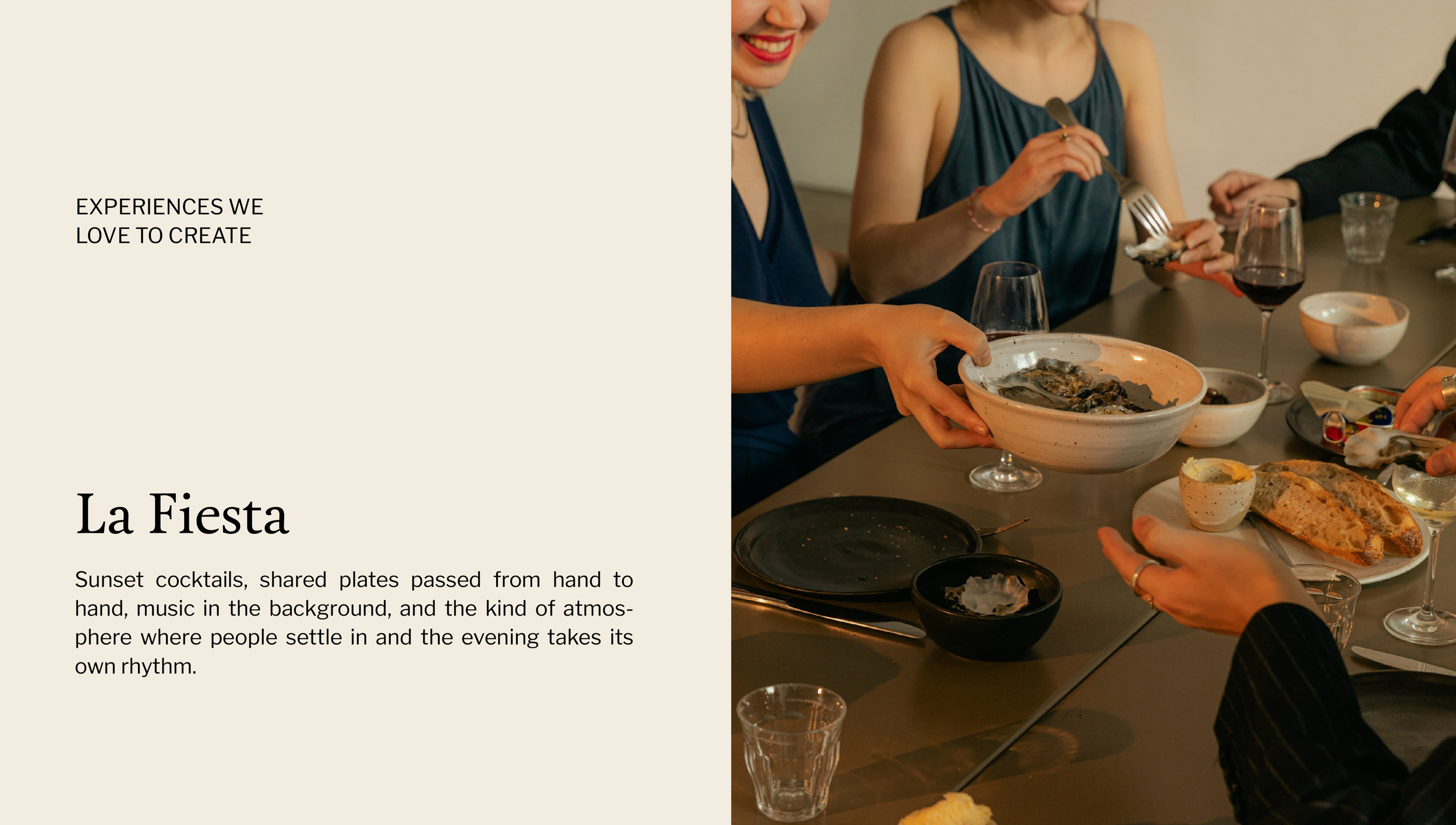 People sitting at a table sharing a meal with food and drinks, including wine and bread, during an evening gathering.