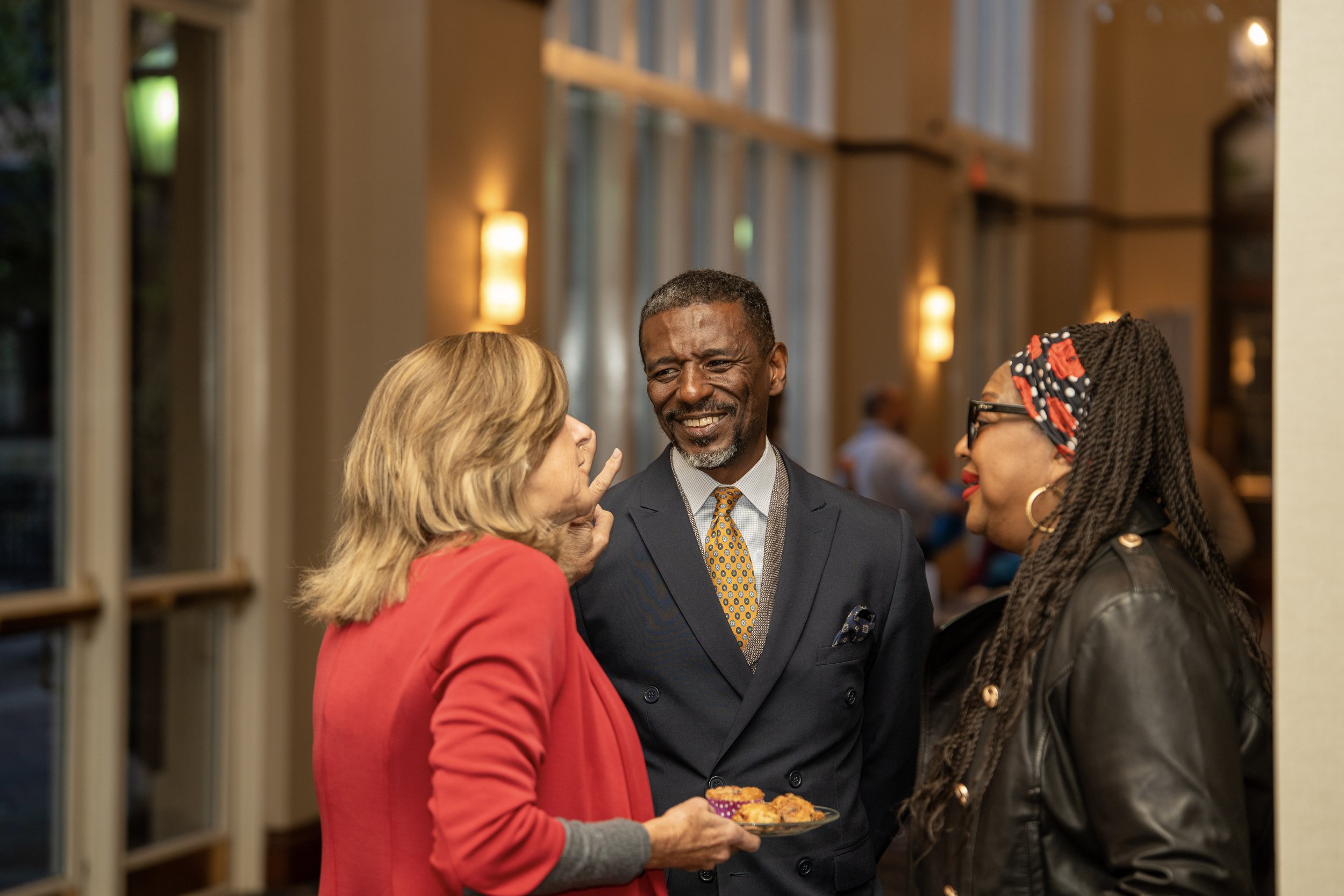 Keynote speaker Carlton hall speaks with two women in conference center foyer