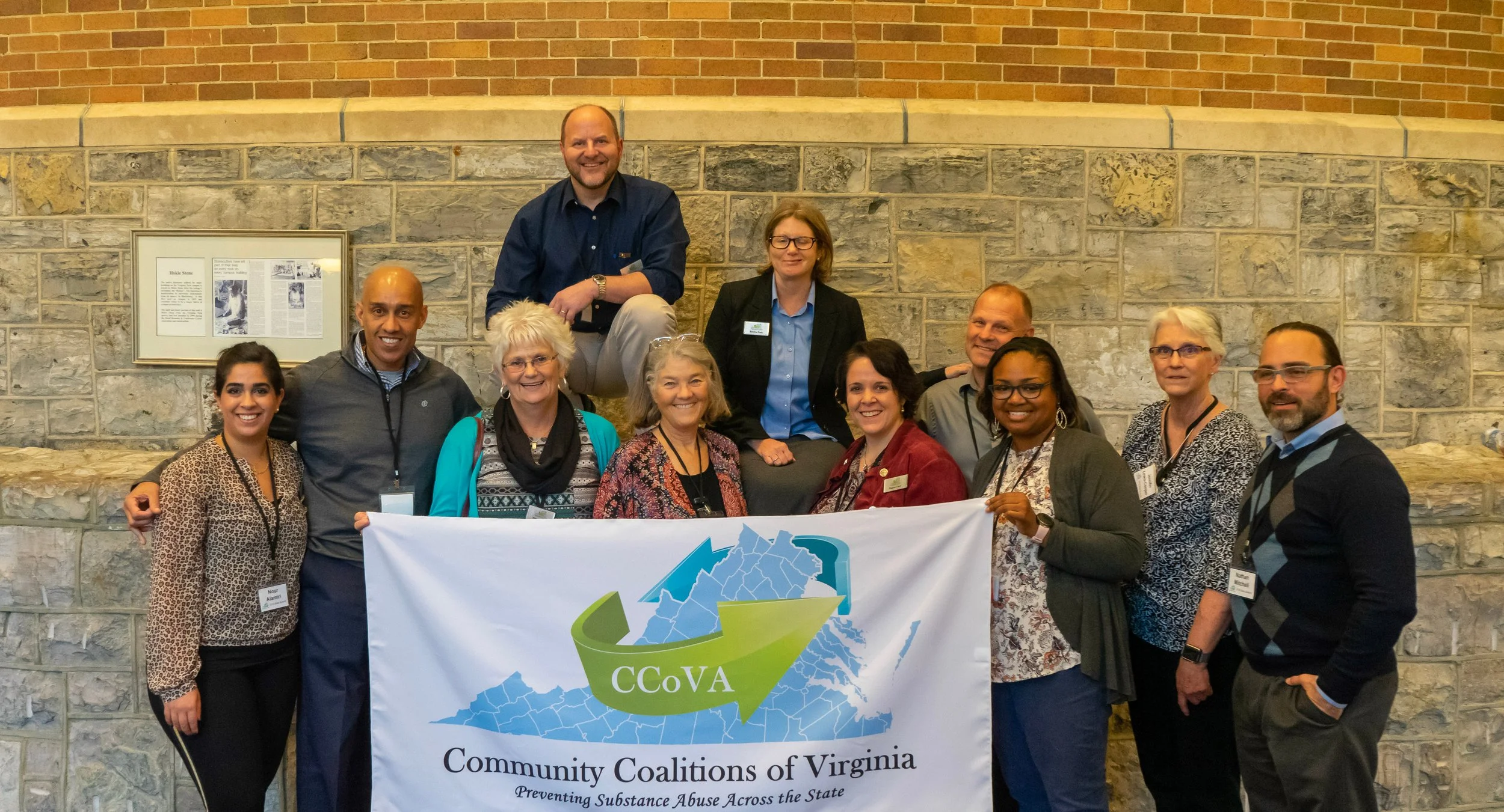 Group of people holding a flag with the logo for Community Coalitions of Virginia