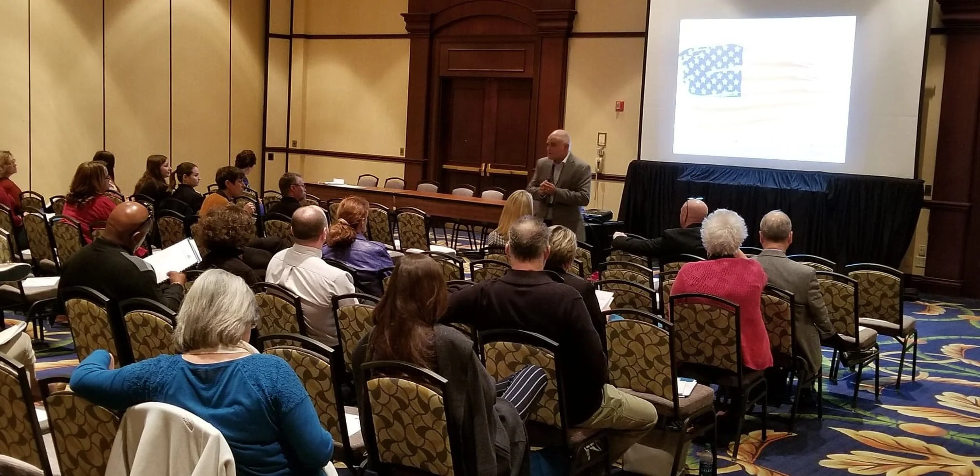 Room of attendees viewing conference presentation