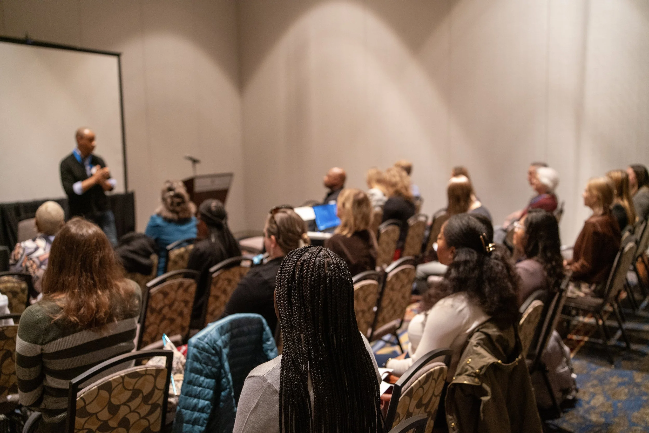 Room full of conference attendees viewing a presentation
