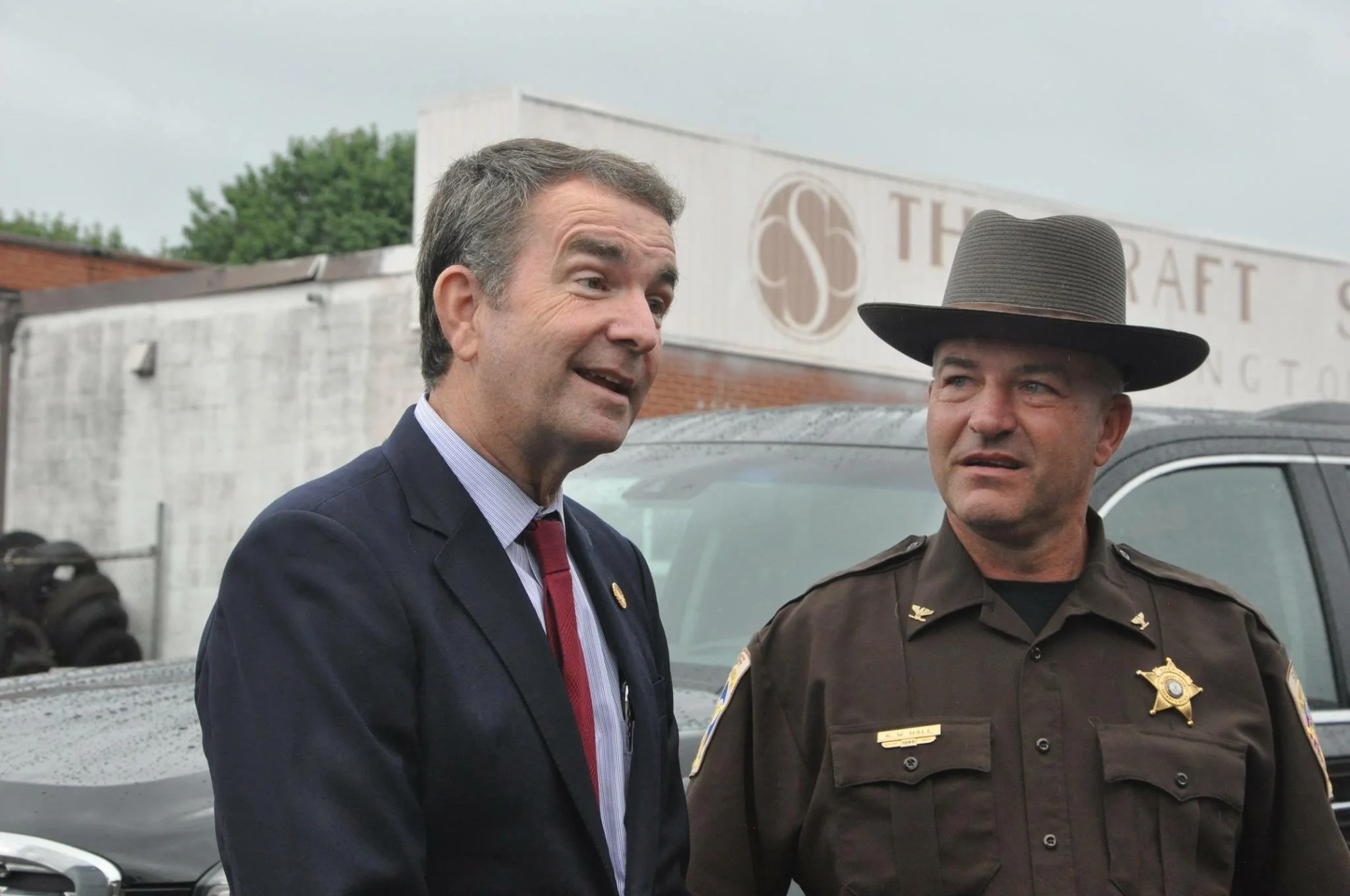 Virginia Governor Ralph Northam speaking while standing next to a uniformed law enforcement officer