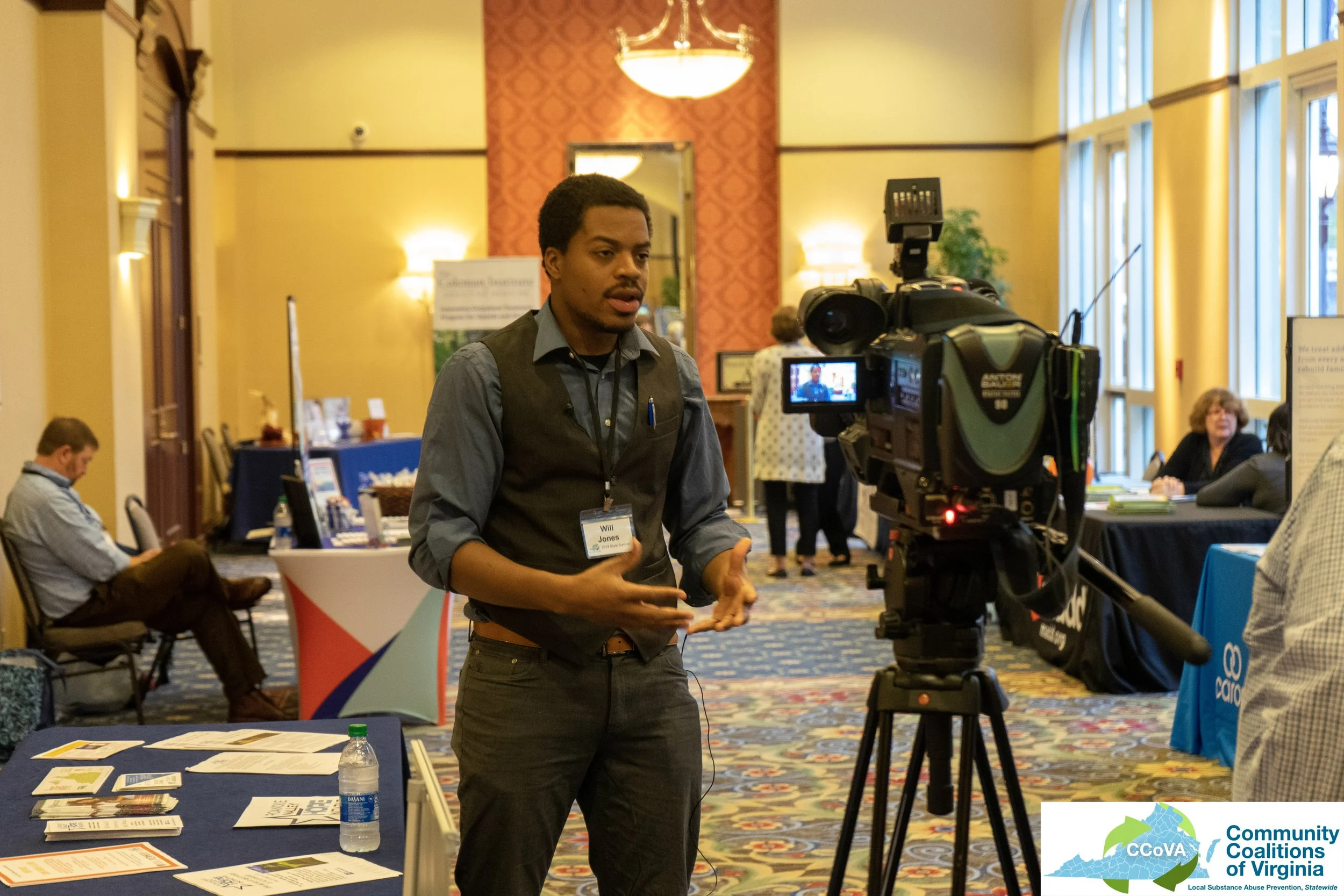Male attendee speaking into television camera while in the main hall of the conference center