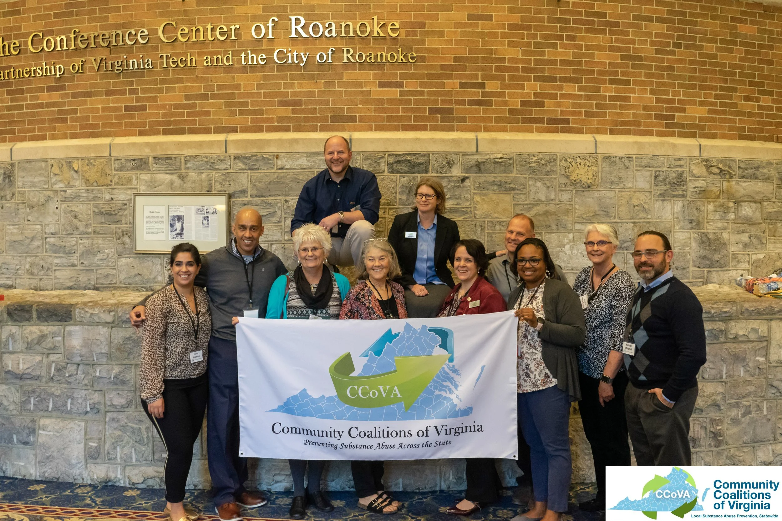 Conference planners posing as a group with a flag reading "Community Coalitions of Virginia"