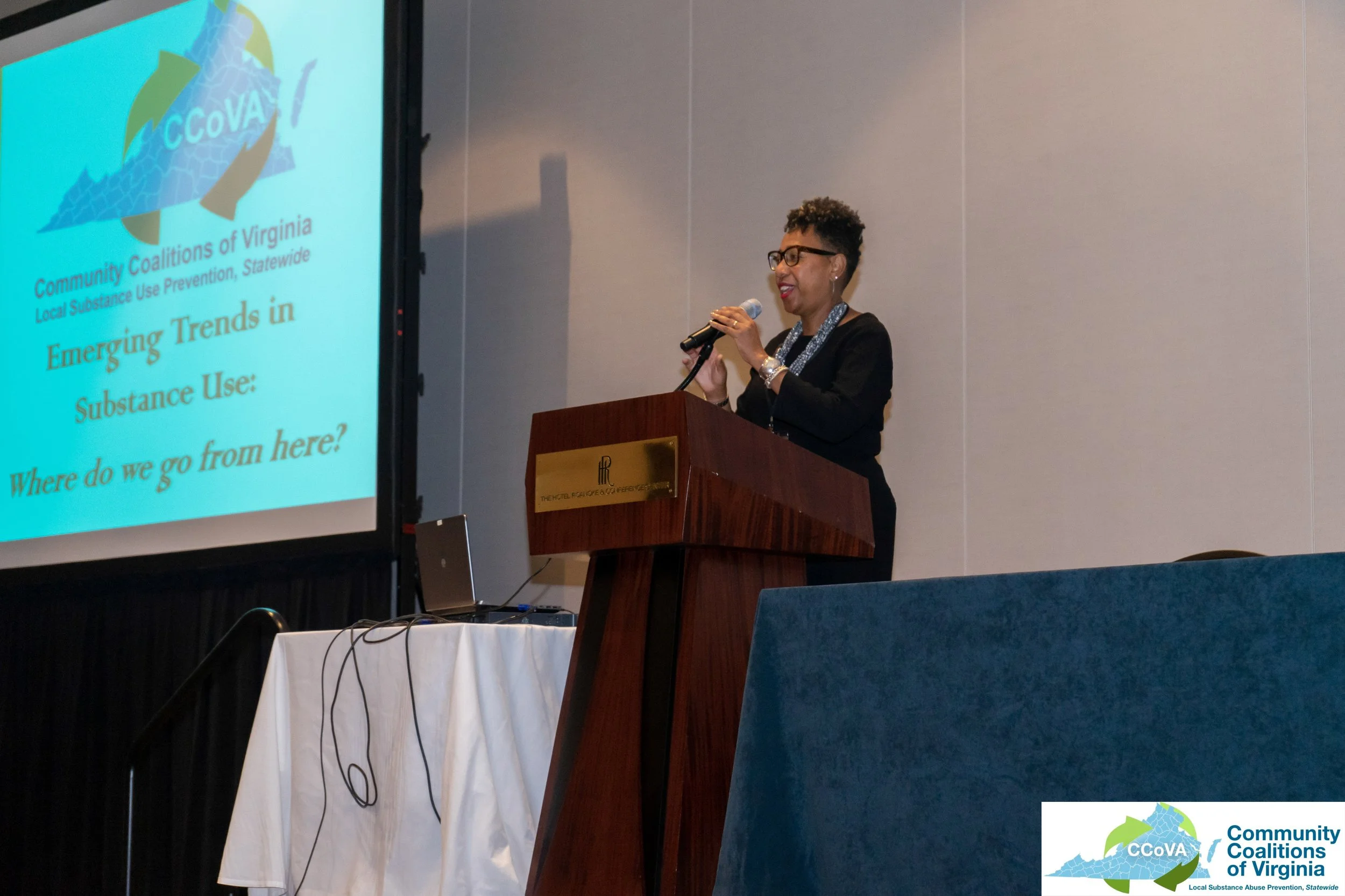 Female presenter at lectern giving opening remarks for the conference