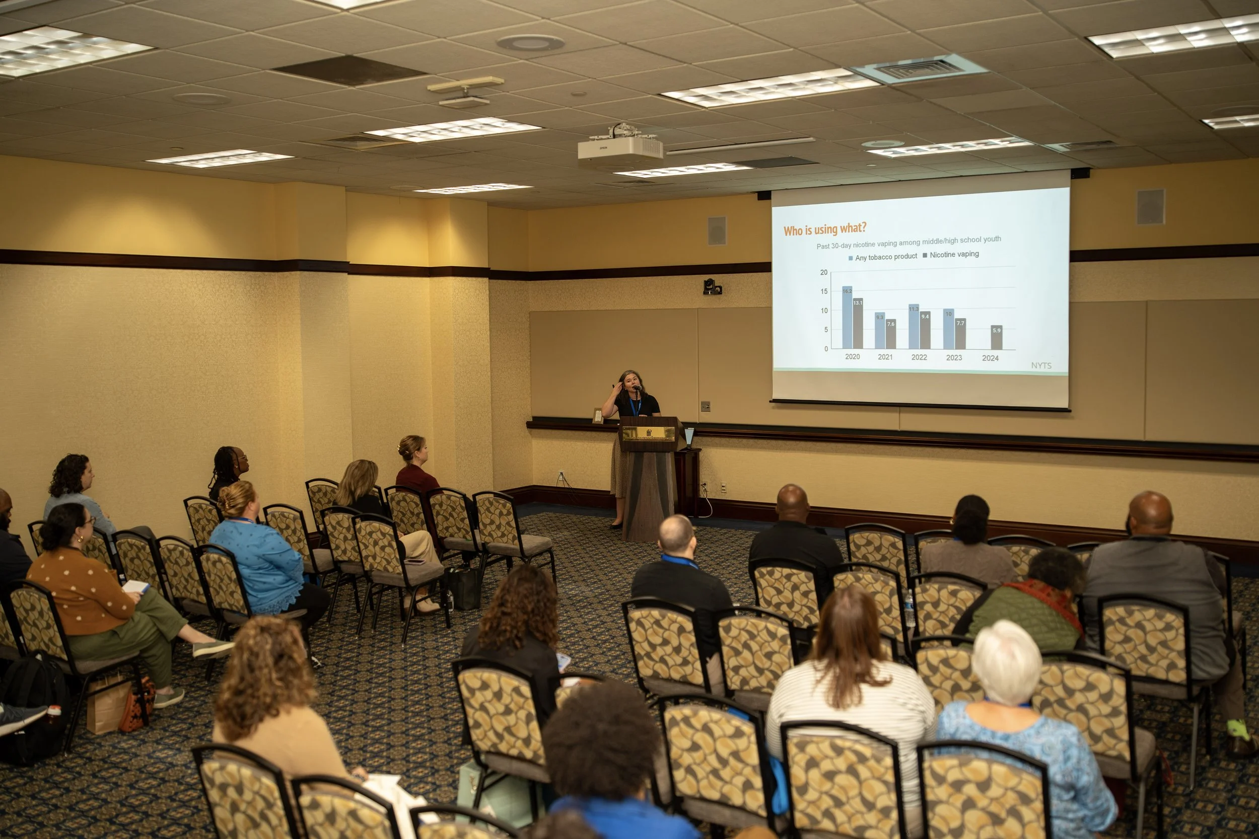 Room of conference attendees viewing a graph on a projector screen