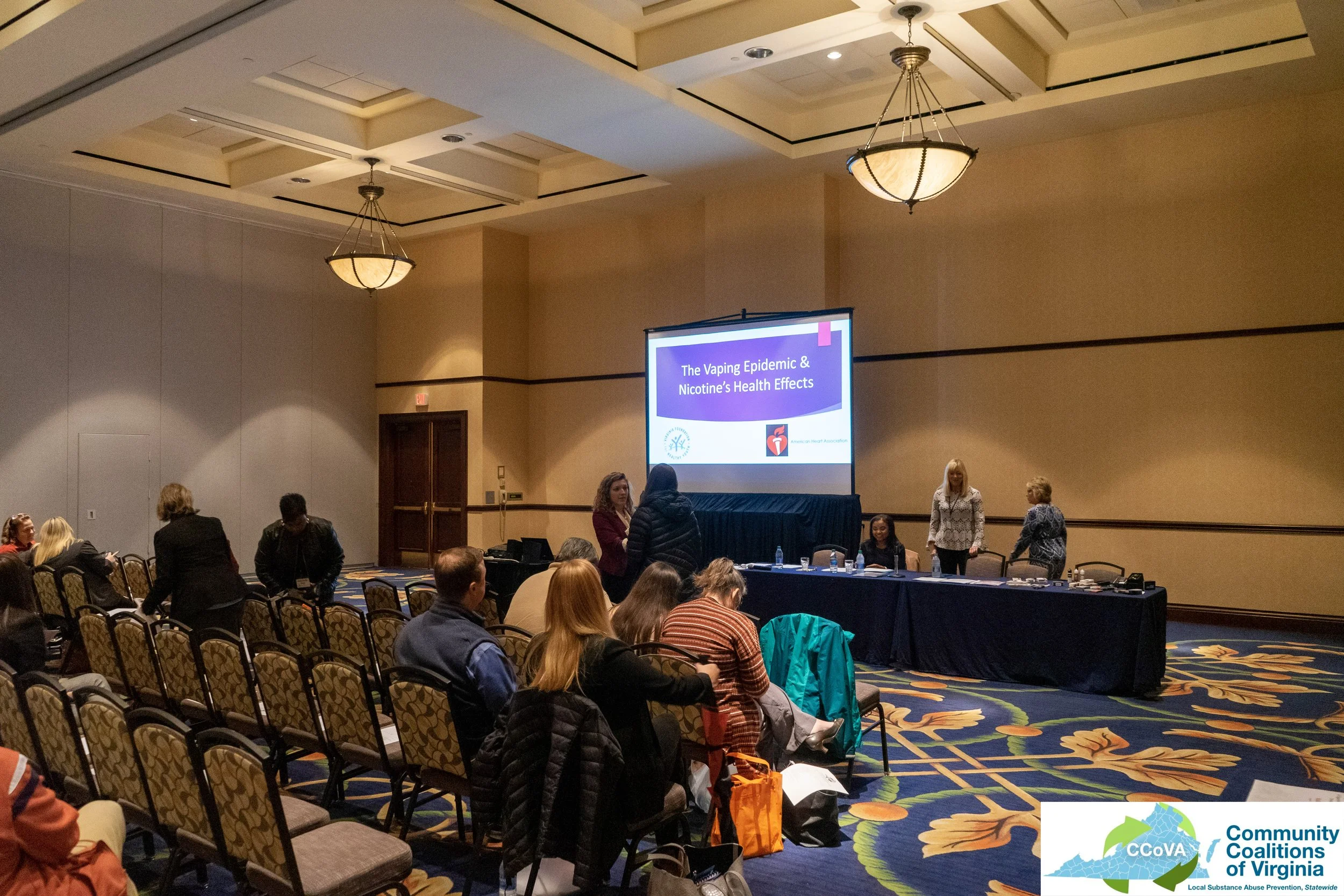 Attendees in conference room waiting for presentation to begin
