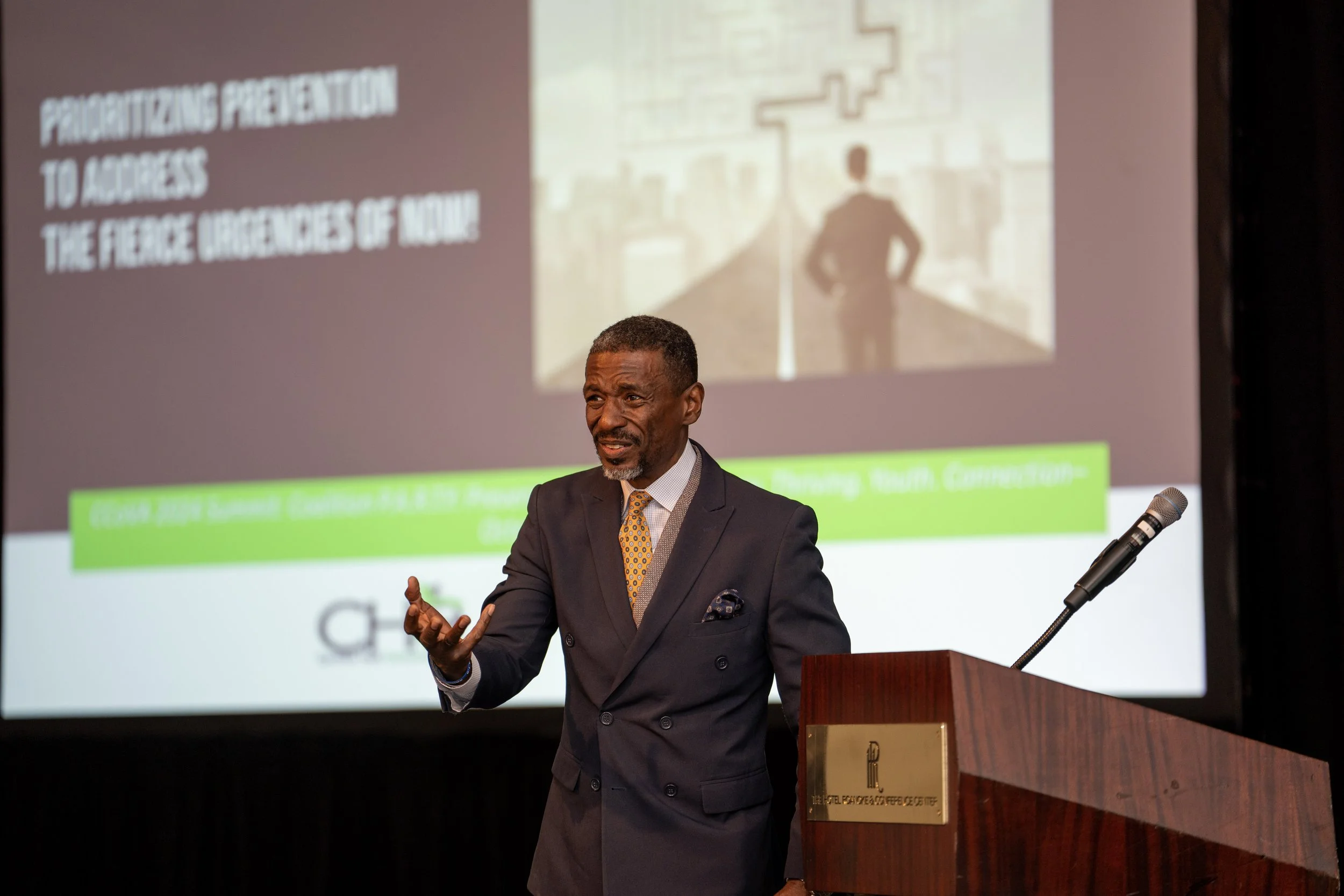 Carlton Hall giving presentation with podium and projector screen