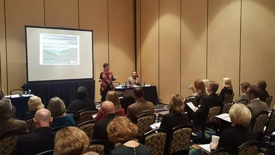 Room of attendees viewing conference presentation