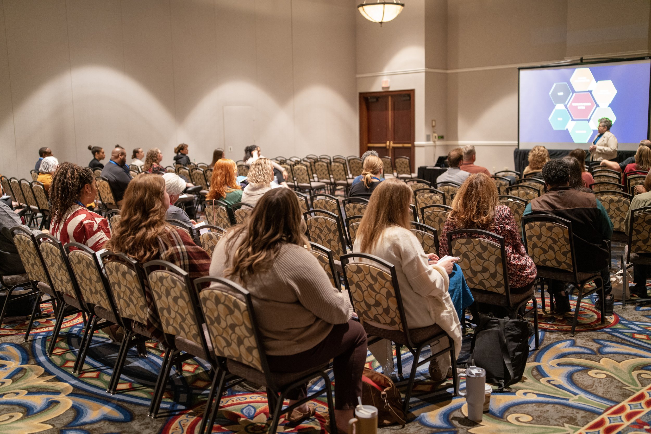 Room full of conference attendees viewing a presentation